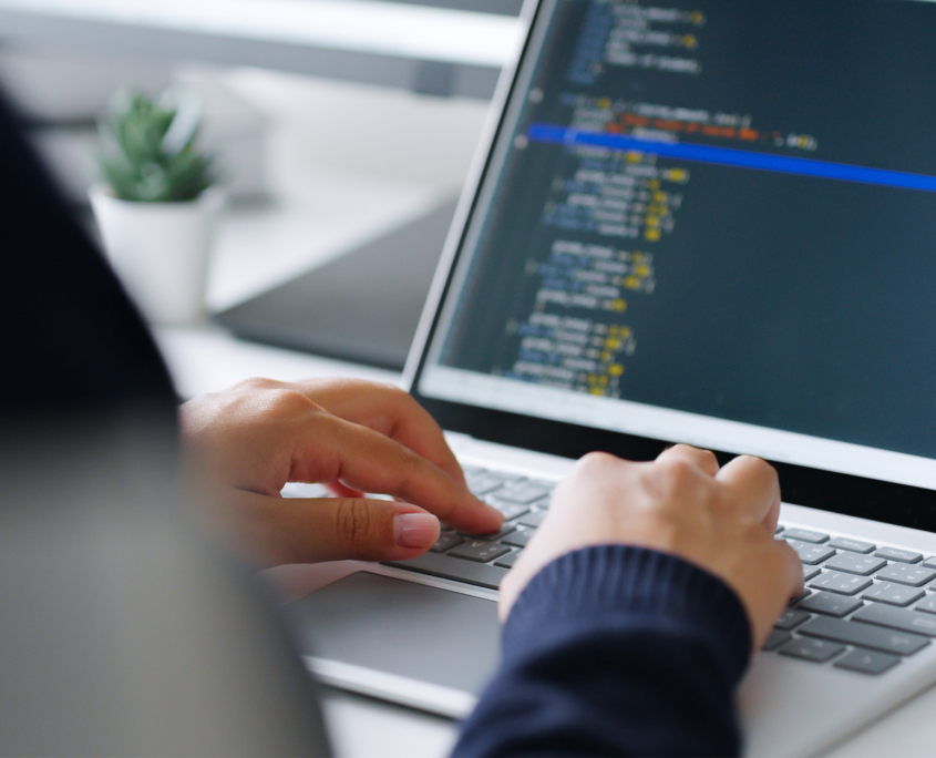 Back View Of A Person Typing Code On Laptop, Over Shoulder View