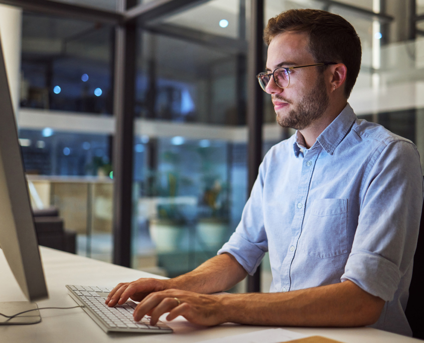 Side View Of Man In Modern Office On Computer