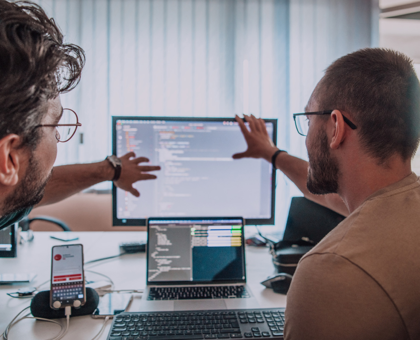 Back View Of Two Developers Collaborating And Looking At Code Shell