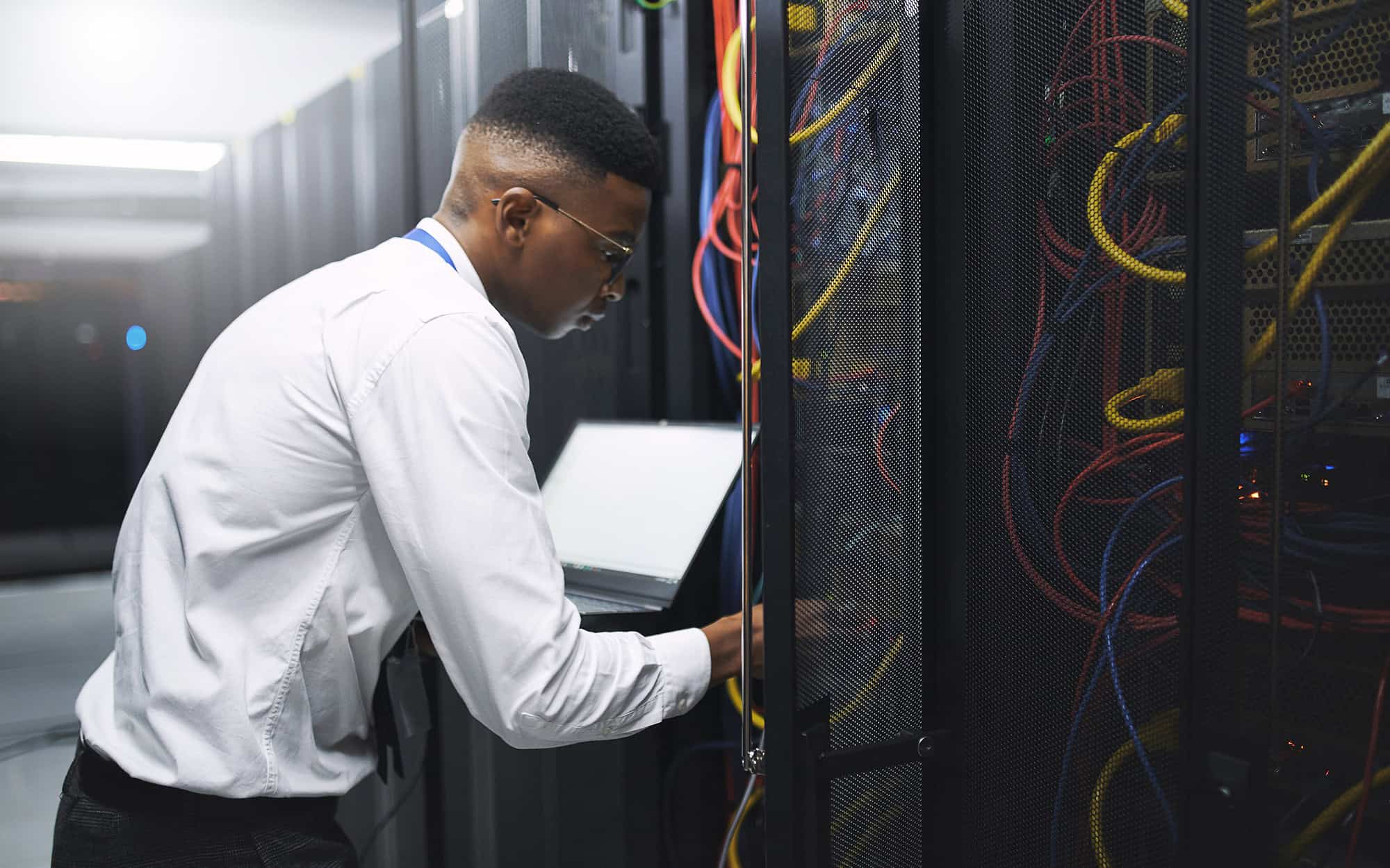 Side View Of Man In Server Room Hooking Up Equipment