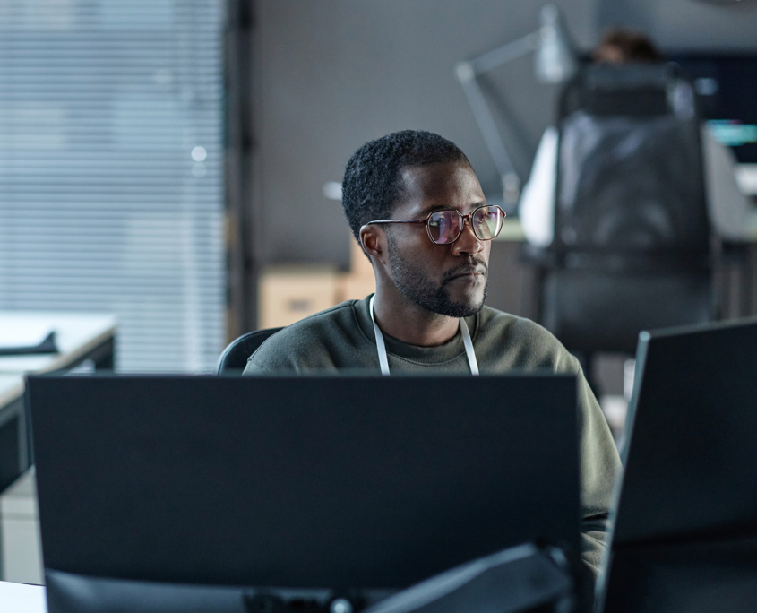 Side View Of Man Looking Seriously At Computer Screens