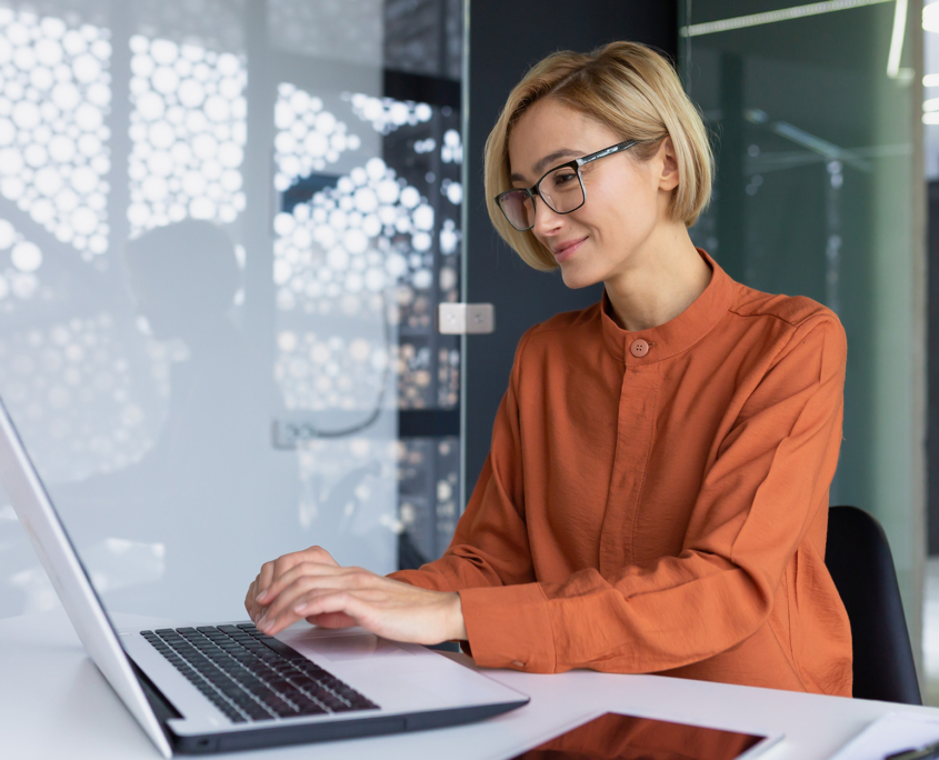 Side View Of Young Woman With Short Haircut Working On A Laptop In Modern Office